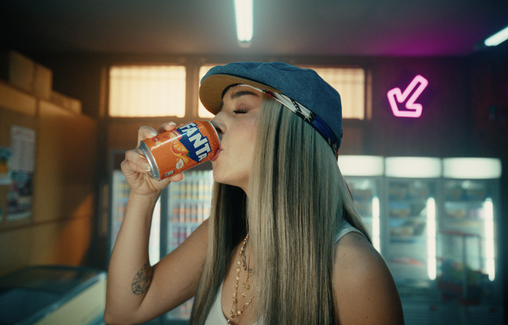 Lola Índigo sipping Fanta in a convenience store